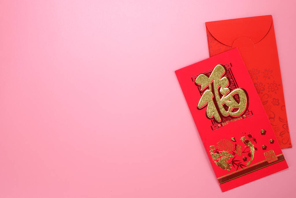 Червоний конверт для китайського Нового року, ізольований на рожевому фоні китайського речення, означає "щастя" і "Всі побажання справджуються"." - Фото, зображення
