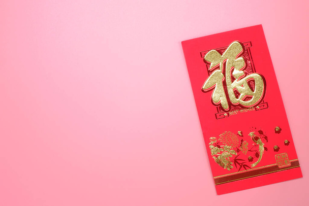 Sobre rojo para Año Nuevo Chino aislado sobre fondo rosa La frase china significa "Felicidad" y "Todos los deseos se hacen realidad"" - Foto, Imagen