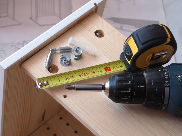 assembling a wooden drawer for a desk with a screwdriver - Photo, Image