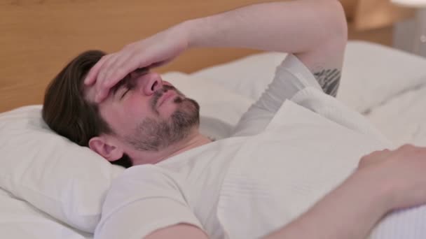 Casual νεαρός άνδρας έχει πονοκέφαλο, ενώ κοιμάται στο κρεβάτι - Πλάνα, βίντεο