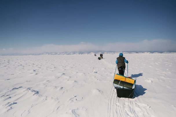 Female tourist walking with  sled dragging on the frozen ice of Lake Baikal. Winter trekking - Foto, afbeelding