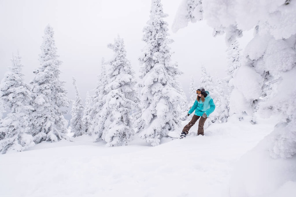 Snowboarder hembra cabalgando sobre nieve de invierno encogido slop en snowboard. Día del polvo, vacaciones de invierno en la estación de esquí - Foto, imagen