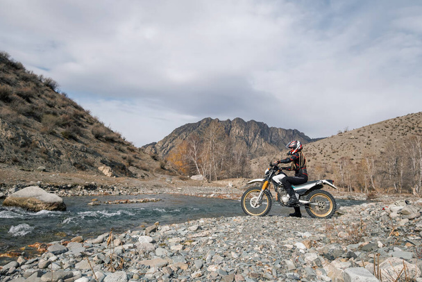 Female motorcyclist seating on Offroad enduro motorcycle in beautiful mountains near the river - Foto, imagen