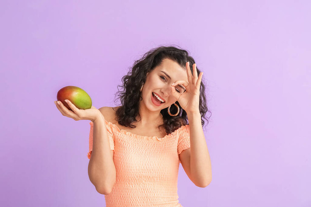 Hermosa mujer con mango fresco mostrando OK en el fondo de color - Foto, imagen