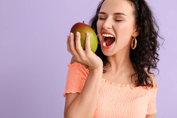 Beautiful woman with fresh mango on color background - Photo, Image