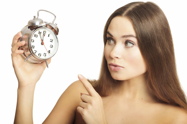 Portrait of the girl showing a finger on an alarm clock, isolated on white background. - Photo, Image