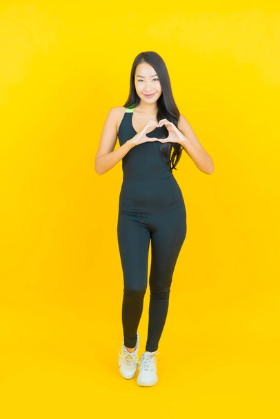 Porträt schöne junge asiatische Frau tragen Fitness-Studio-Outfit bereit für die Übung auf gelbem Hintergrund - Foto, Bild
