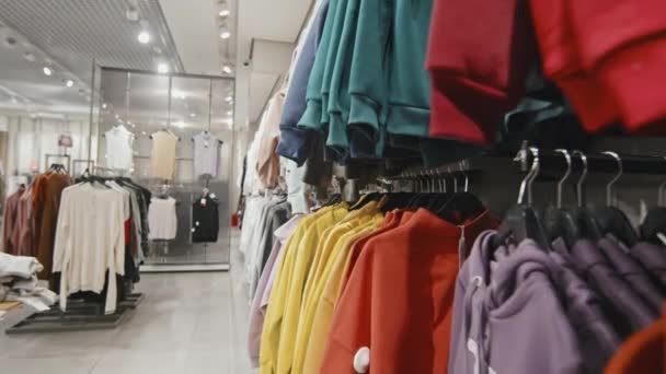 Nincs ember dolly lövés divatos alkalmi ruhák élénk színek lóg állványok női osztály stílusos áruház - Felvétel, videó