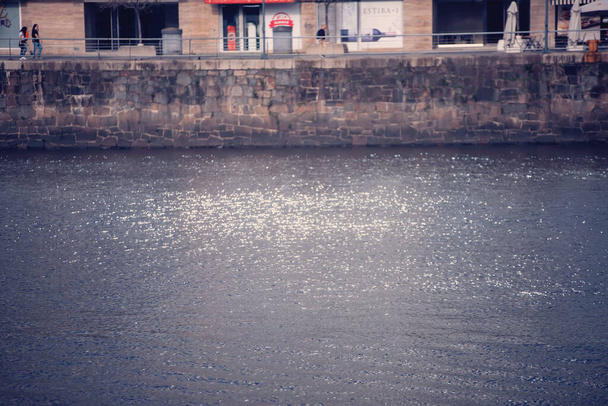 een verticaal schot van een waterdruppel op de pier in een plas - Foto, afbeelding