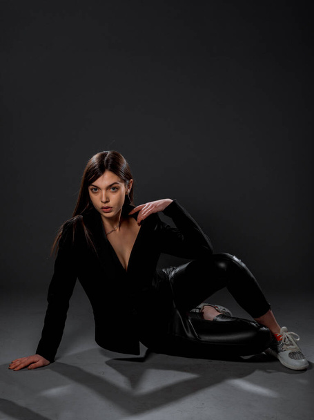 Atraktivní mladá modelka pózující ve stylových černých kalhotách, top a teniskách - Fotografie, Obrázek