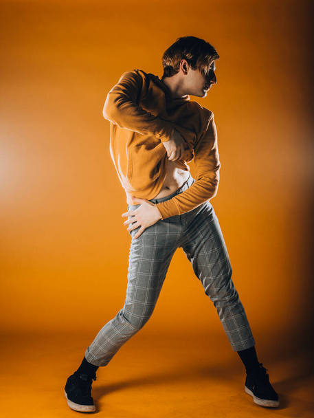 Muskulöser männlicher Tänzer bei einer Tanzeinlage im orangefarbenen Studio - Foto, Bild