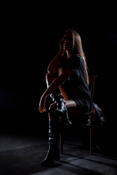 Body shot μιας στιλάτης γυναίκας που ποζάρει σε μοντέρνο μαύρο χιτώνα και ψηλές μπότες γόνατος - Φωτογραφία, εικόνα