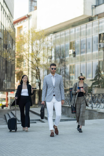 Three business people are walking toegther towards the company - 写真・画像