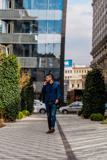 Moda hombre de negocios que tiene conversación telefónica caminando en el centro de la ciudad - Foto, Imagen
