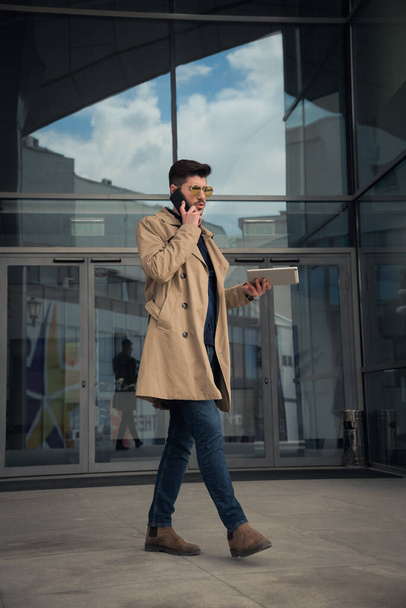 Městský podnikatel mluví po telefonu, zatímco přemýšlí o společnosti a chůzi - Fotografie, Obrázek