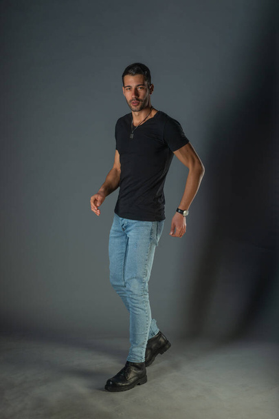 Sesión de fotos del estudio de un hombre guapo posando en jeans y camisa negra - Foto, imagen