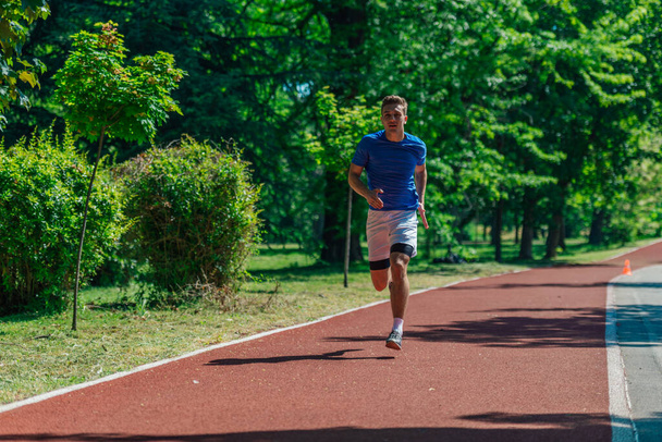 Handsome man jogging during sunny morning out on the race track - 写真・画像