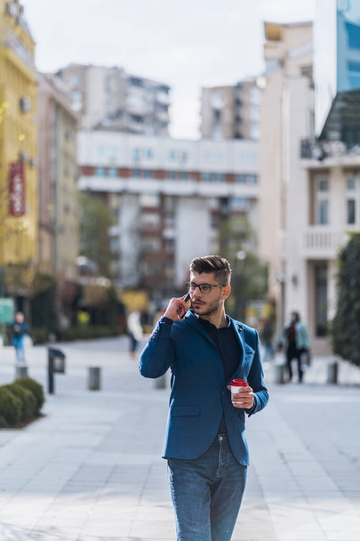 市内中心部を歩きながら携帯電話で話す現代のビジネスマン - 写真・画像