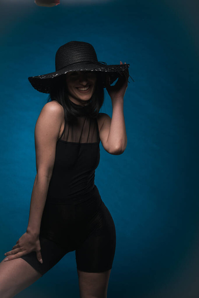 Привлекательная и элегантная девушка позирует в черном наряде, улыбаясь - Фото, изображение