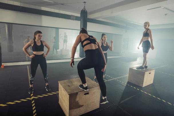 Fit νεαρές γυναίκες που κάνουν κουτί squat ασκήσεις στο γυμναστήριο crossfit - Φωτογραφία, εικόνα