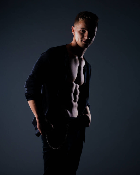 Vrolijke jonge Europese man draagt unbuttoned shirt poseren in moderne studio - Foto, afbeelding