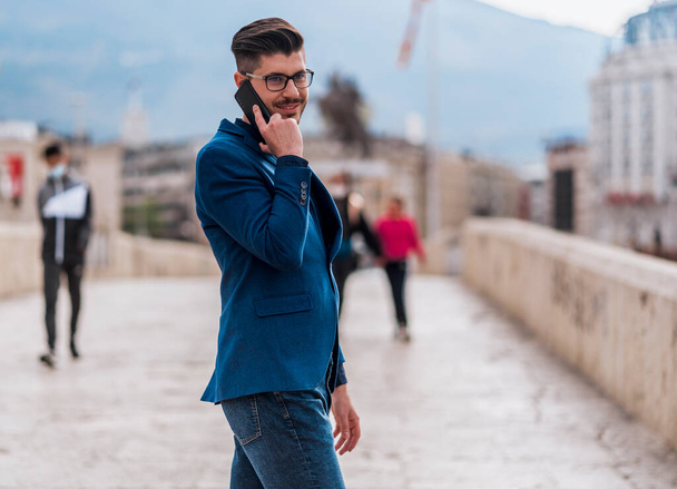 Handsome young man walking and talking on mobile phone in the city - Foto, Imagen