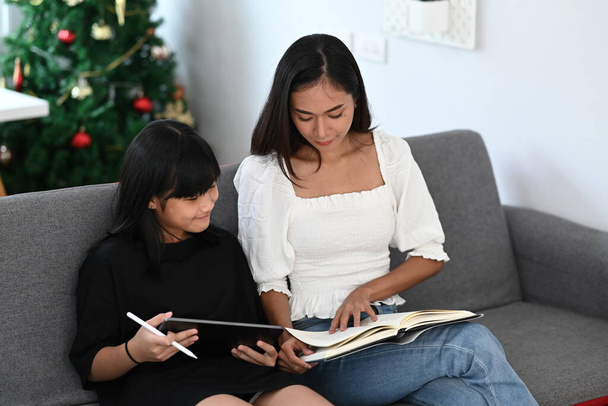 Mutter hilft Tochter bei Hausaufgaben am digitalen Tablet zu Hause Online-Bildung, Lernen zu Hause, Homeschooling-Konzept. - Foto, Bild