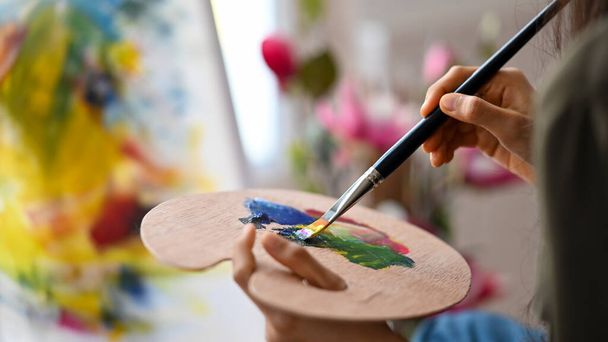 Bliżej artystka kobieta trzyma paletę kolorów i kolor mieszany dla projektu malarstwa akrylowego. - Zdjęcie, obraz