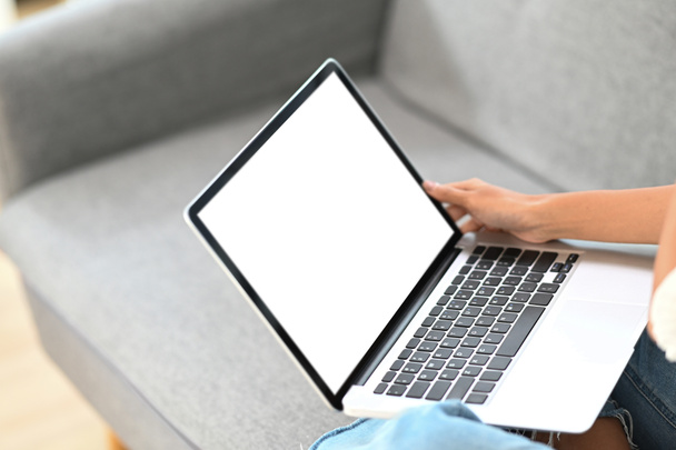 Close up vista mulher segurando mock up laptop enquanto sentado no sofá em casa. - Foto, Imagem