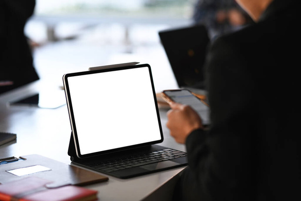 Κλείσιμο προβολής του υπολογιστή tablet στο τραπέζι του γραφείου με businesswoman γραπτών μηνυμάτων σε ένα έξυπνο τηλέφωνο.  - Φωτογραφία, εικόνα