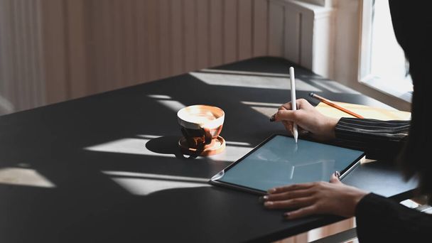 Vágott felvétel fiatal végrehajtó nő rajz a számítógépen tabletta fehér üres képernyőn, miközben tervezi, hogy az üzleti és ül a modern íróasztal. irodai háttérrel. - Fotó, kép