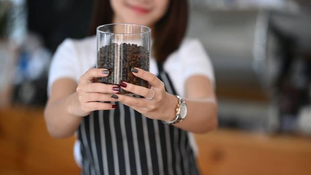 Cropped shot coffee shop owner holding a glass of coffee bean at her cafe. - 写真・画像