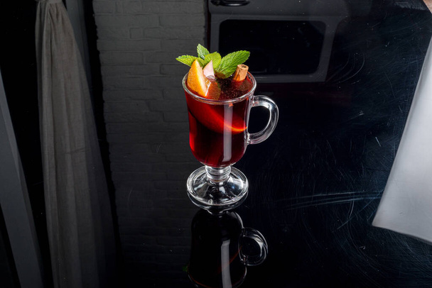 Mulled wine in a glass transparent glass on a black background with reflection - Foto, imagen