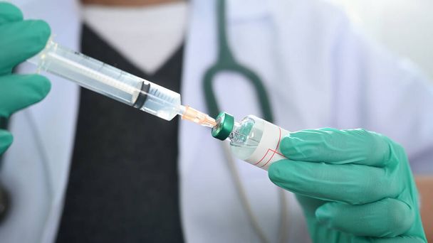 Visão de perto do médico segurando uma seringa para injetáveis e uma vacina.  - Foto, Imagem