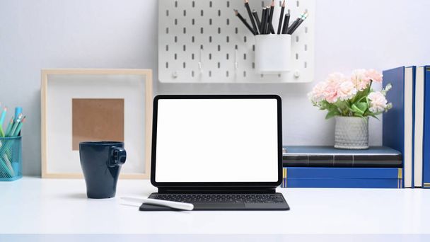 Mock up tablet computer with empty screen, books and office supplies on white table. - 写真・画像