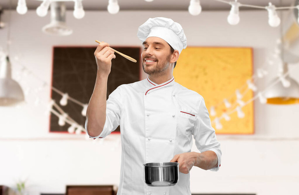happy smiling male chef with saucepan tasting food - Valokuva, kuva