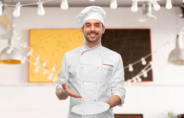 happy smiling male chef holding empty plate - Foto, Imagen
