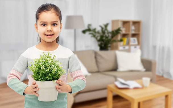 happy smiling girl holding flower in pot at home - Photo, Image