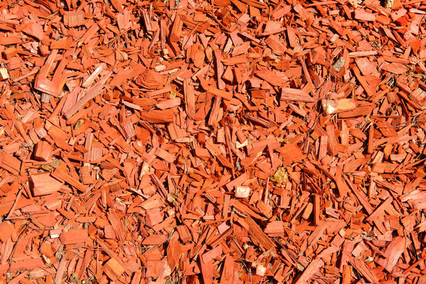 Red wood chips background and texture, close up. Wooden sawdust on sunny day. - Фото, изображение