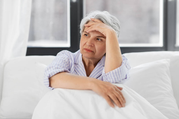 senior woman with headache sitting in bed at home - Фото, зображення