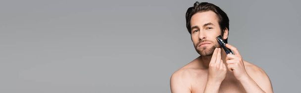 shirtless man using electric razor isolated on grey, banner - Foto, immagini
