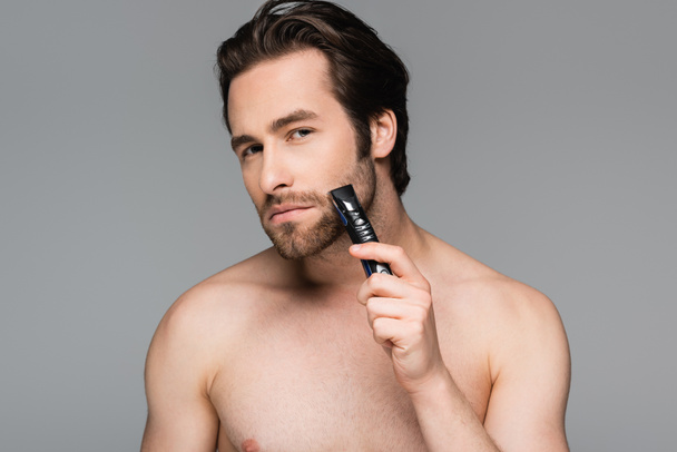 félmeztelen férfi vágás szakáll elektromos trimmer elszigetelt szürke - Fotó, kép