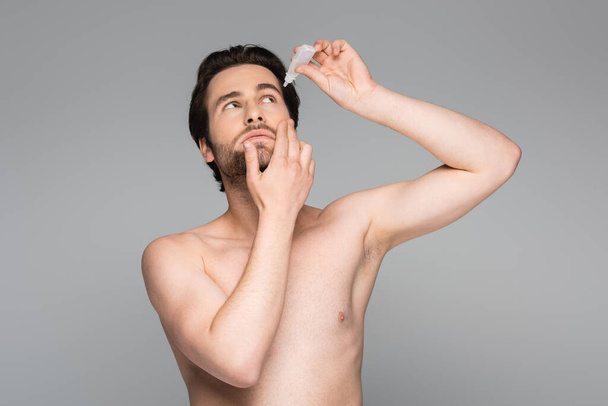 shirtless man applying eye drops isolated on grey - Photo, Image