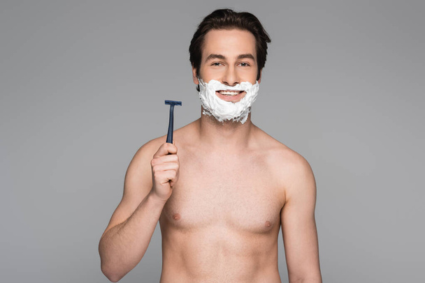 shirtless man with foam on face holding safety razor isolated on grey - Foto, Imagem