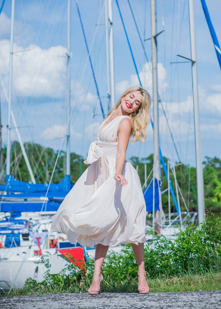 Милая блондинка в яхт-клубе. Женщина в летящем шелковом белом платье на открытом воздухе, расслабиться время - Фото, изображение