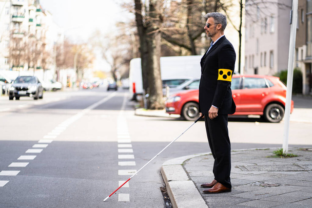 Blind Man Walking On Sidewalk Holding Stick Wearing Armband - Foto, Bild
