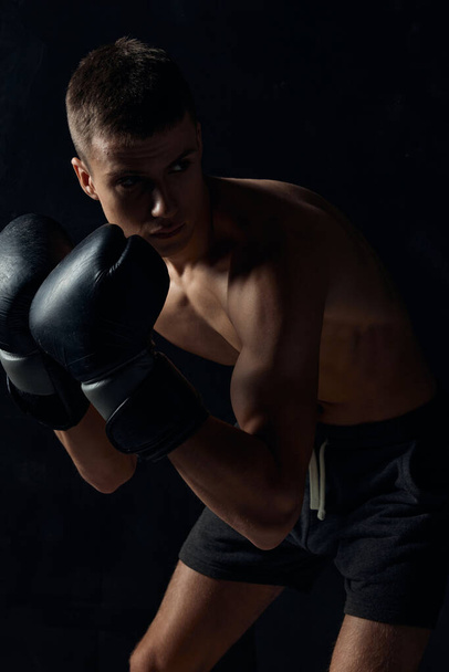 boxer in handschoenen op een zwarte achtergrond gebogen naar beneden  - Foto, afbeelding