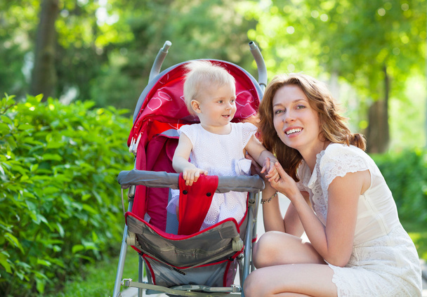  gyönyörű fiatal nő gyermekével, egy babakocsi  - Fotó, kép