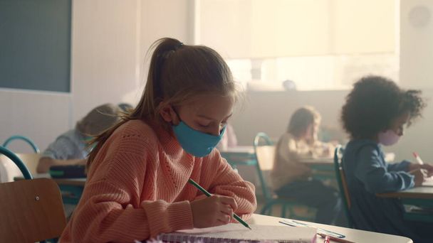 Student w masce ochronnej studiujący w szkole podczas pandemii wirusa korony - Zdjęcie, obraz