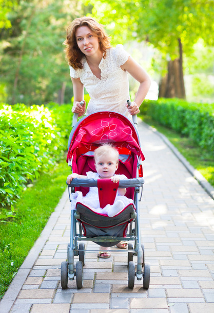  schöne junge Frau mit ihrem Kind im Kinderwagen  - Foto, Bild